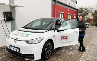 Hier handelt es sich um ein E-Fahrzeug der KDE Transport GmbH, das gerade von der Kurierin betankt wird.