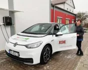 Eine Kurierin der KDE Transport steht an ihrem E-Auto für regionale Botenfahrt. Das Auto wurde gerade an der KDE-Wallbox von der Photovoltaikanlage beladen.