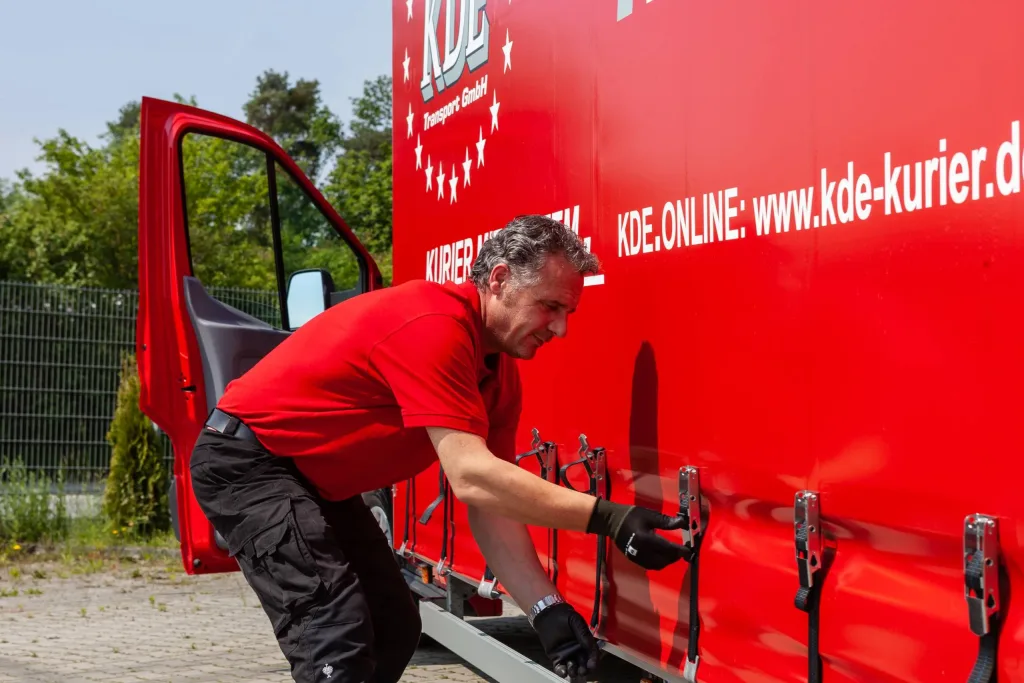 Planen LKW wird geöffnet Ein Kurier der KDE Transport GmbH öffnet gerade die Seite eines Planen-LKW.
