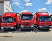 Das Foto zeigt Drillinge: 3 neue, rote LKW der KDE Transport GmbH, die für Direkt- und Kurierfahrten bereitstehen.