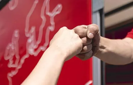 Zwei Kuriere schlagen nach gutem Teamwork ein. Sie haben auf einen Planen LKW der KDE Transport GmbH wertvolle Ware sicher verladen.