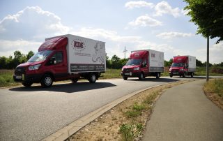3 LKW der KDE Transport GmbH sind auf einer Landstraße unterwegs.