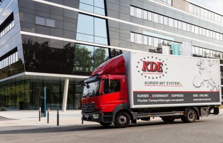 Ein LKW der KDE Transport GmbH fährt durch Erlangen und gerade an einem Siemens-Gebäude vorbei.