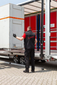 Planen LKW Beladung Das Foto zeigt einen Beladevorgang auf einen Planen-LKW. Die Ware wird mit einem Gabelstapler von der Seite beladen, ein KDE-Kurier weist den Staplerfahrer an, um eine sichere Beladung zu gewährleisten.