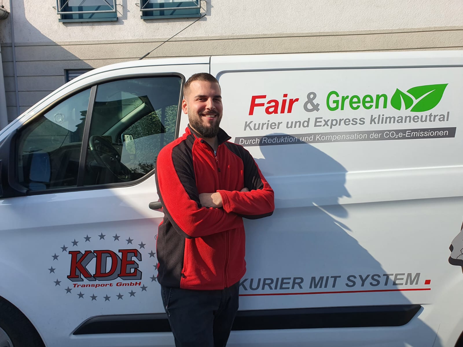 Rodgauer Kurier am Fahrzeug Ein Kurierfahrer der KDE Transport GmbH steht neben seinem Kurierfahrzeug am Parkplatz der Niederlassung von KDE in Rodgau.